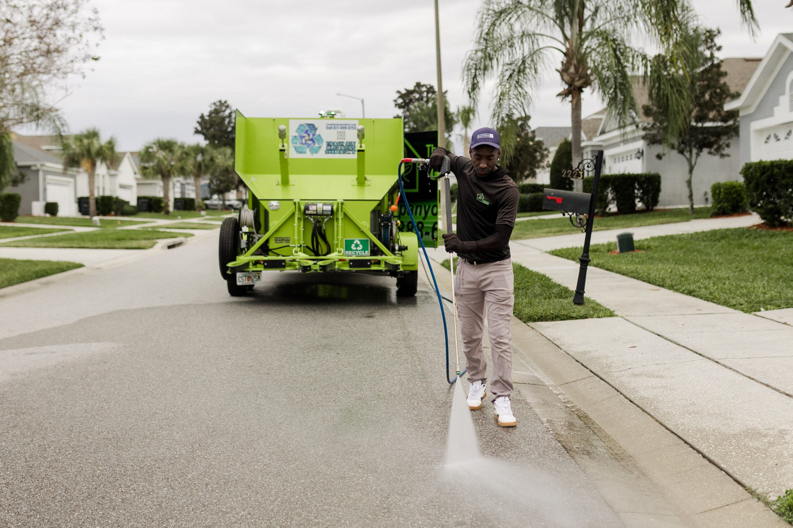 Technician pressure washing a residential curb