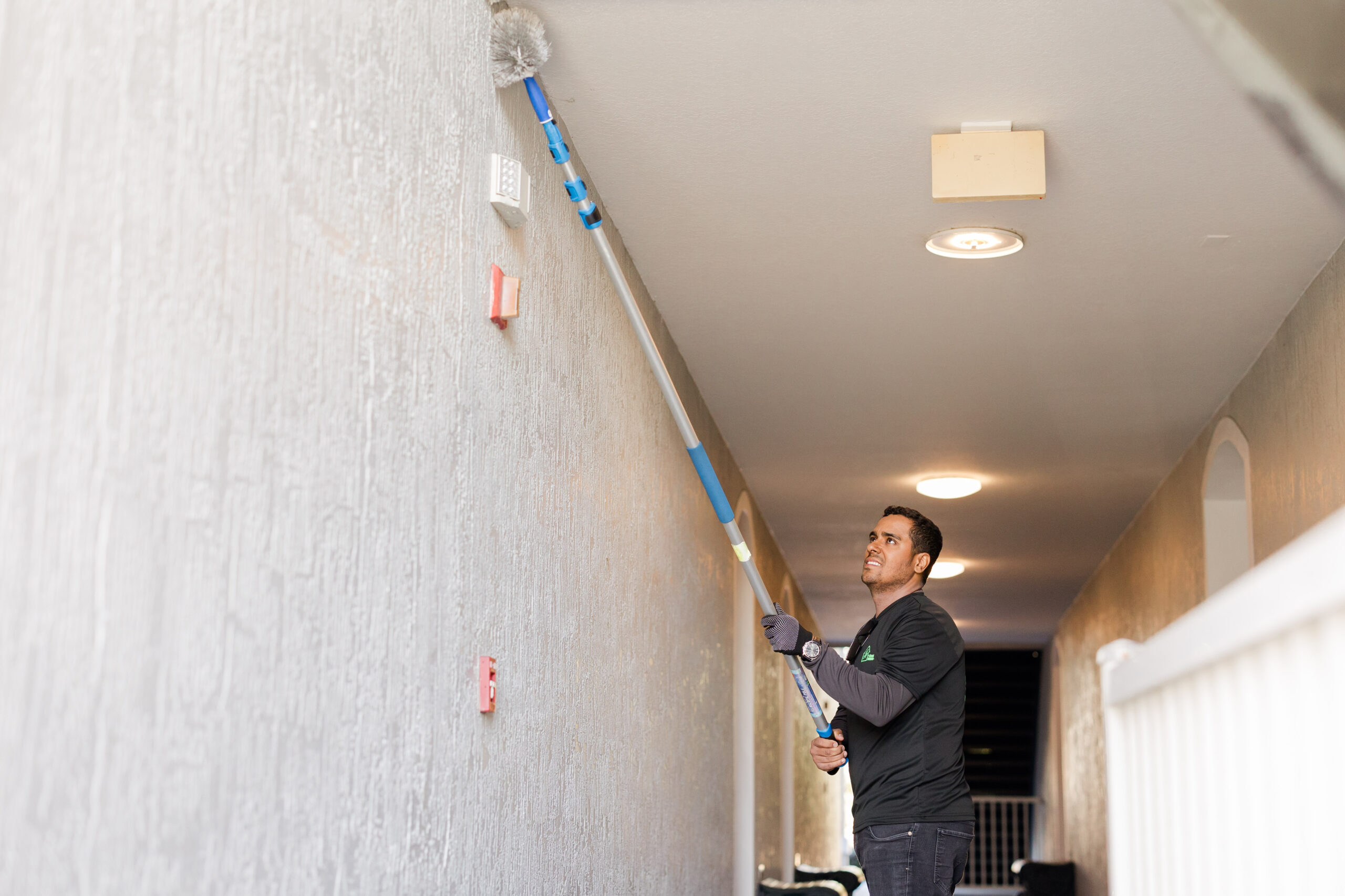 Post-construction cleaner removing dust from high walls and ceilings